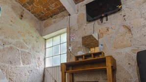Une pièce avec un mur en pierre, une table en bois, une cheminée et un téléviseur fixé au mur.