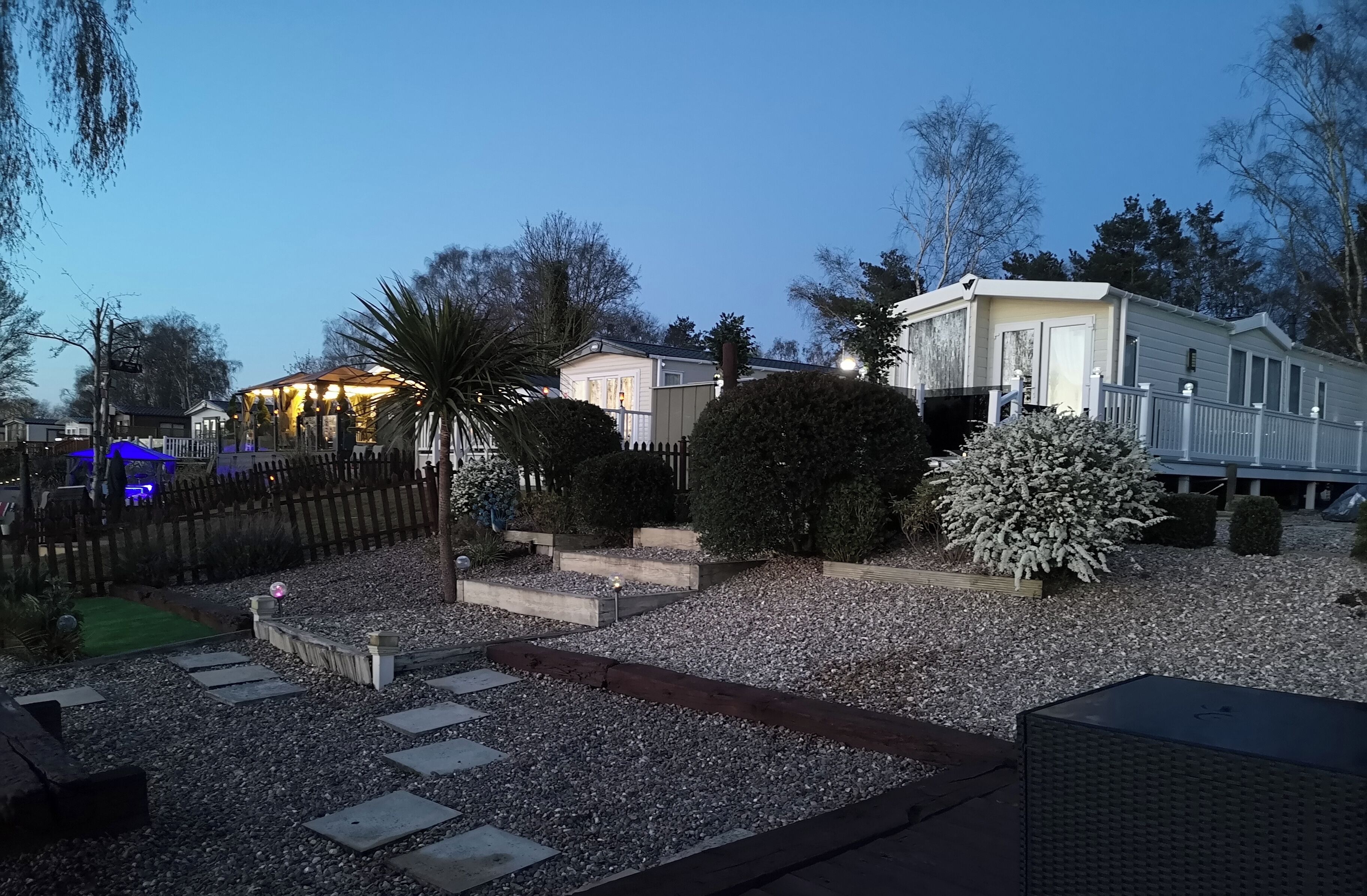 A residential area with a well-maintained garden, a gazebo, and a mobile home.