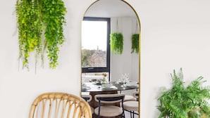 A dining area with a view through an archway, featuring hanging plants and a dining table set for four.