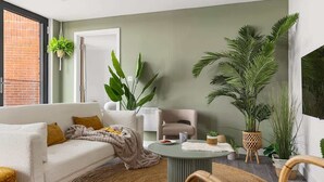A modern living room with a white sofa, a round coffee table, and a large potted plant.