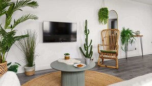 A modern living room with a round table, a television, and various plants.