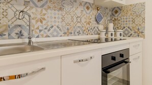 A kitchen with a modern design, featuring a stainless steel sink, a built-in oven, and a patterned backsplash.