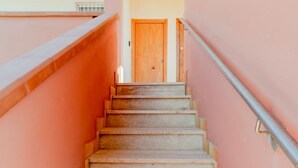 A staircase leading to a wooden door, with a metal handrail on the right.