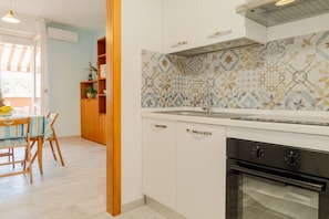 A kitchen with white cabinets, a patterned backsplash, and a built-in oven.