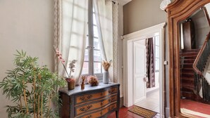 A room with a wooden dresser, a mirror, a potted plant, and a staircase. - Apartment 'La Tourelle Des Cordeliers' with Private Terrace, Shared Garden and Wi-Fi (Loches)