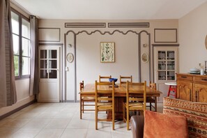 A dining area with a wooden table, chairs, and a patterned sofa.