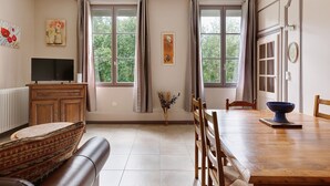 A living room with a sofa, TV, dining table, and chairs. - Apartment 'La Tourelle Des Cordeliers' with Private Terrace, Shared Garden and Wi-Fi (Loches)