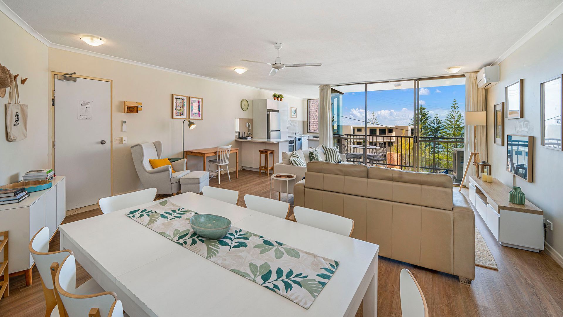 A modern apartment with a dining area, a living room, and a balcony with a view of the city.