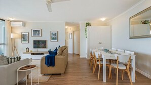 Moderni olohuone, jossa on sohva, ruokapöytä tuoleineen ja suuri peili.