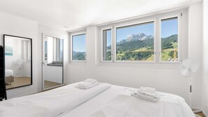 A bedroom with two beds, a large mirror, and a view of mountains.