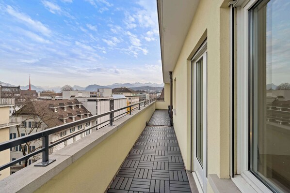 Un balcón con vista a un paisaje urbano y montañas a lo lejos.