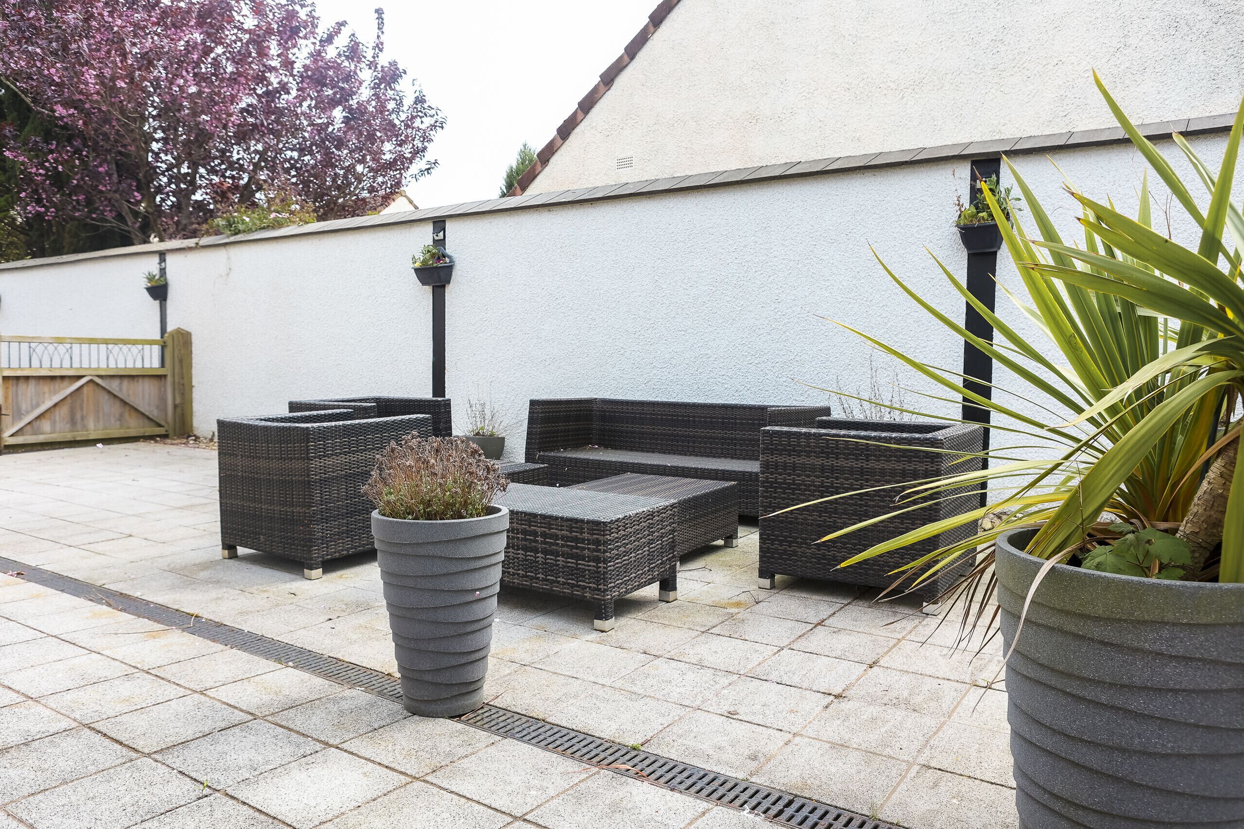 An outdoor patio with wicker furniture and large planters.