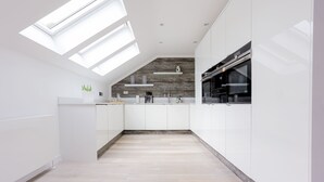 Una cucina moderna con lucernari, mobili bianchi e una parete decorata in legno.