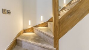 Una scala in legno con illuminazione integrata, una ringhiera e un interruttore a parete.