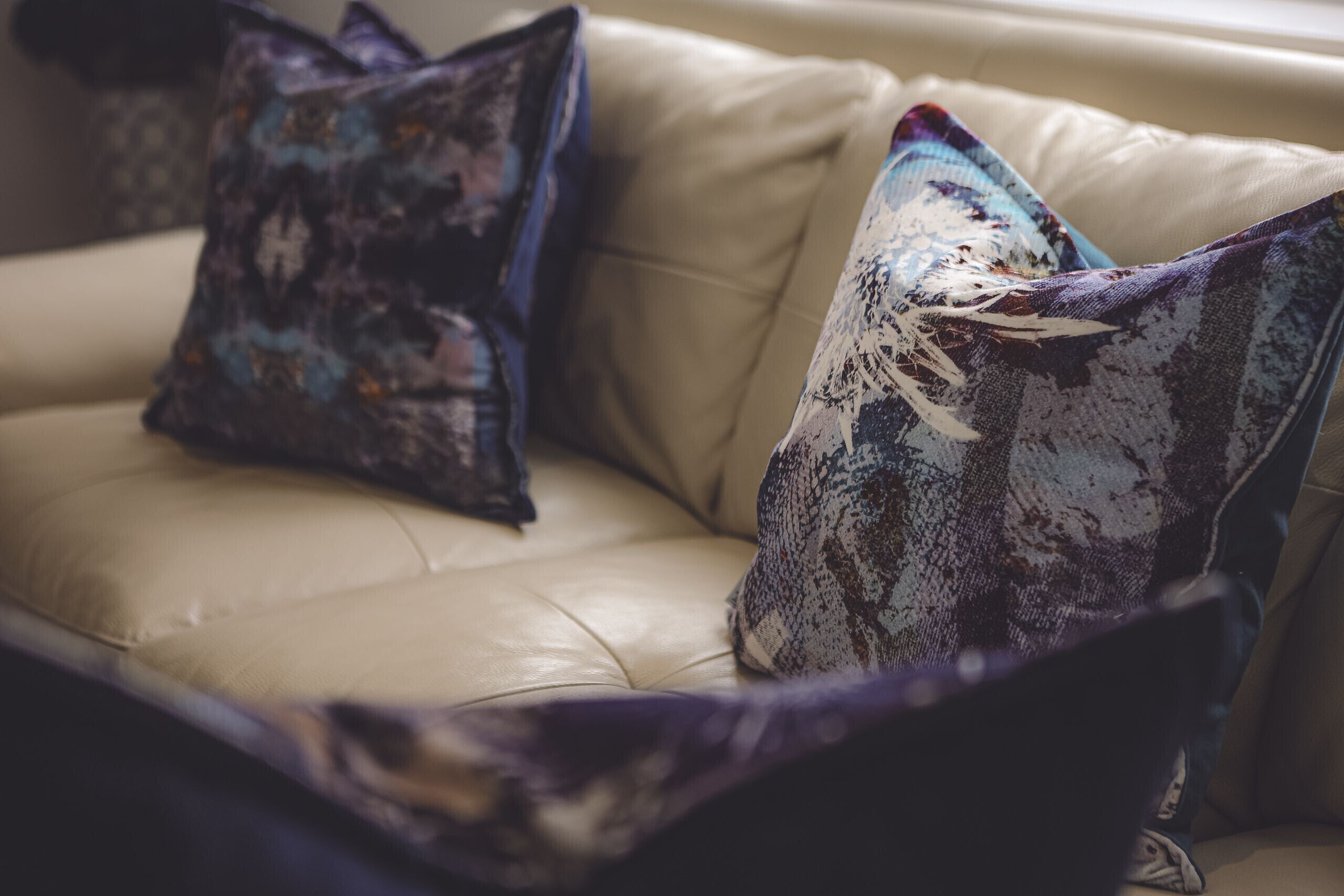 A beige leather sofa with two decorative pillows.