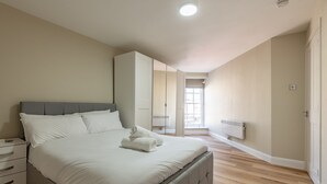 A bedroom with a large bed, a nightstand, a wardrobe, and a radiator.