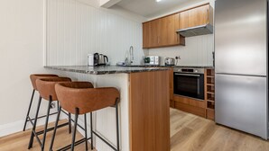 A modern kitchen with a central island, wooden cabinets, stainless steel appliances, and bar stools.