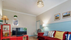 A living room with a red sofa, a television, a red cabinet, and a lamp.