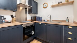 A modern kitchen with dark cabinets, a built-in oven, a microwave, and a sink.