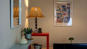 A room with a red table, a lamp, a framed map, and a mirror.
