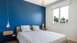 A bedroom with a bed, bedside tables, a hanging light fixture, and a window with a view. - Holiday Home 'Maison De Vacances Oceanides' with Private Terrace, Wi-Fi and Air Conditioning (Capbreton)