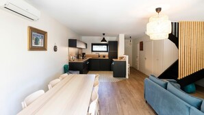 A modern kitchen with black cabinets, a wooden dining table, and a blue sofa. - Holiday Home 'Maison De Vacances Oceanides' with Private Terrace, Wi-Fi and Air Conditioning (Capbreton)