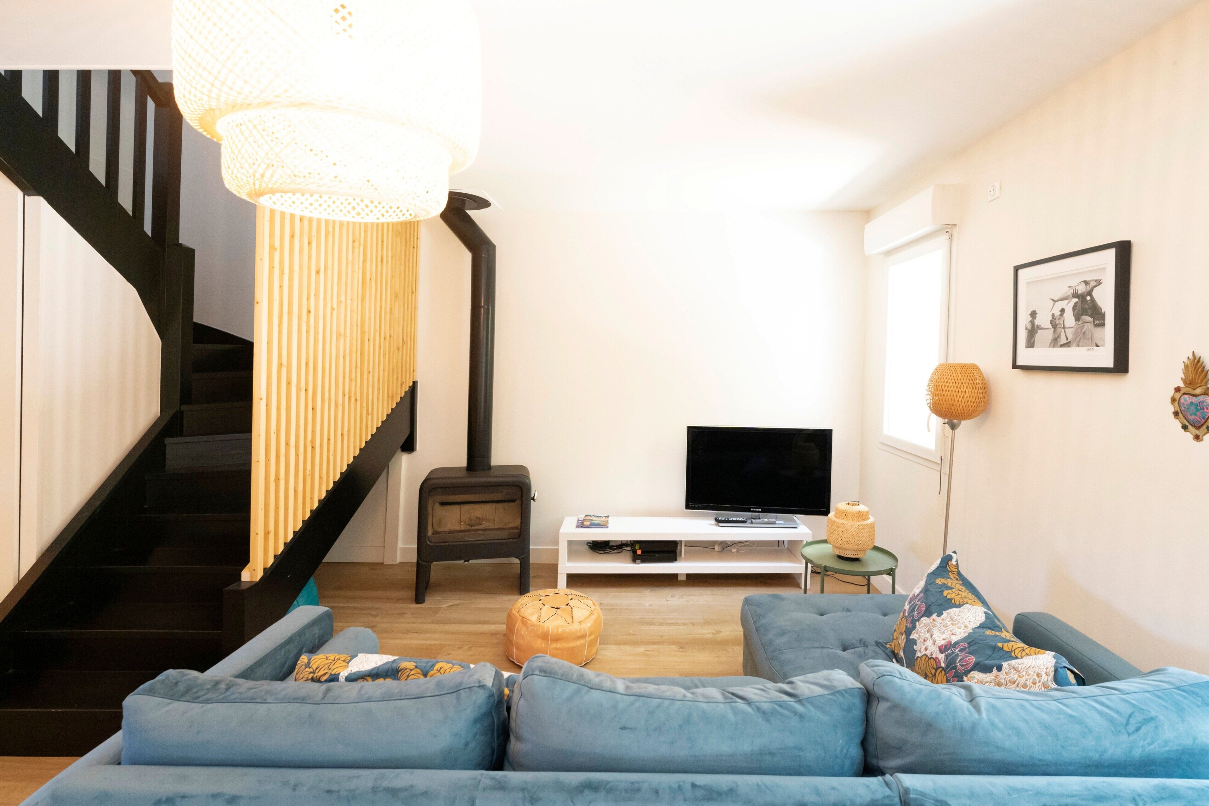 Ein Wohnzimmer mit Treppe, einer Sofagarnitur, einem Fernseher und einem Kamin.