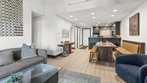 A modern living room with a sofa, coffee table, and a dining area with a bench and table.