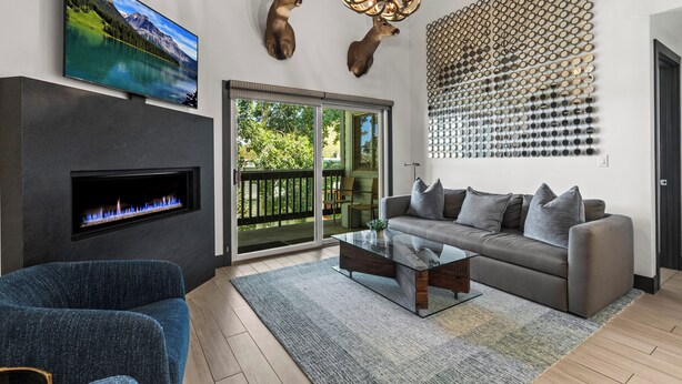 A modern living room with a fireplace, a large flat-screen TV, a sofa, and a coffee table.
