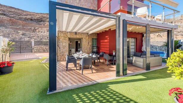 Une terrasse extérieure moderne, dotée d’un espace repas, de sièges et offrant une vue sur le paysage environnant.