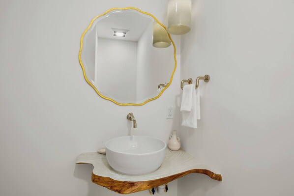 A bathroom with a white sink, a mirror with a gold frame, and a towel rack. - Siesta Beachfront Paradise - Infinity Pool & Spa! (Sarasota)