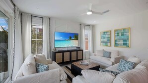 A living room with a TV, white sofas, a coffee table, and artwork on the wall.
