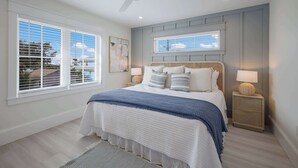 A bedroom with a bed, two bedside tables, a ceiling fan, and a window with blinds.