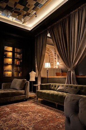 A cozy living room with a green sofa, a patterned rug, and a bookshelf filled with books.
