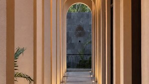A corridor with arches and a stone wall in the background.