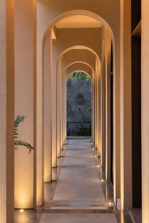 A corridor with arches and a stone wall in the background.