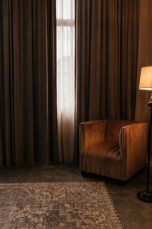 Ein Zimmer mit einem braunen Ledersofa, einem gemusterten Teppich und einer Lampe.
