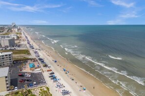 A coastal hotel with a long beachfront, parking, and a view of the ocean.