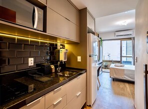 A modern kitchen with a built-in stove, a sink, and a countertop with a soap dispenser. There is a window with a view of a building outside.