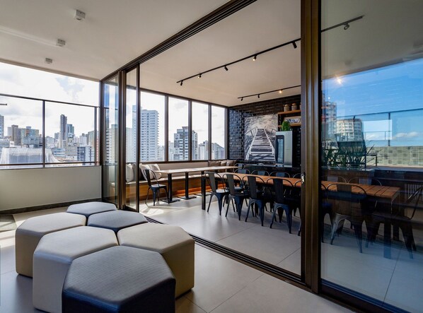 A modern living room with a city view, a dining area, and a kitchen with a brick backsplash.