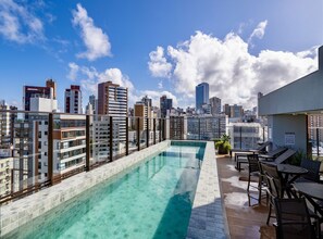 A rooftop pool with a city skyline view, lounge chairs, and a sign indicating 535 homes.