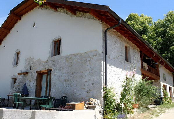 A rustic building with a balcony, a table with chairs, and potted plants.