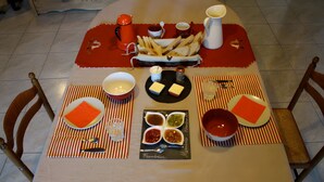 Une table à manger dressée avec des assiettes, des bols, un panier de frites et des condiments.