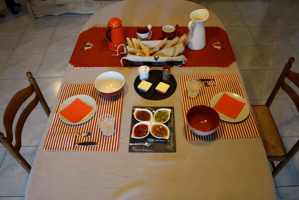 A dining table set with plates, bowls, a basket of fries, and condiments.