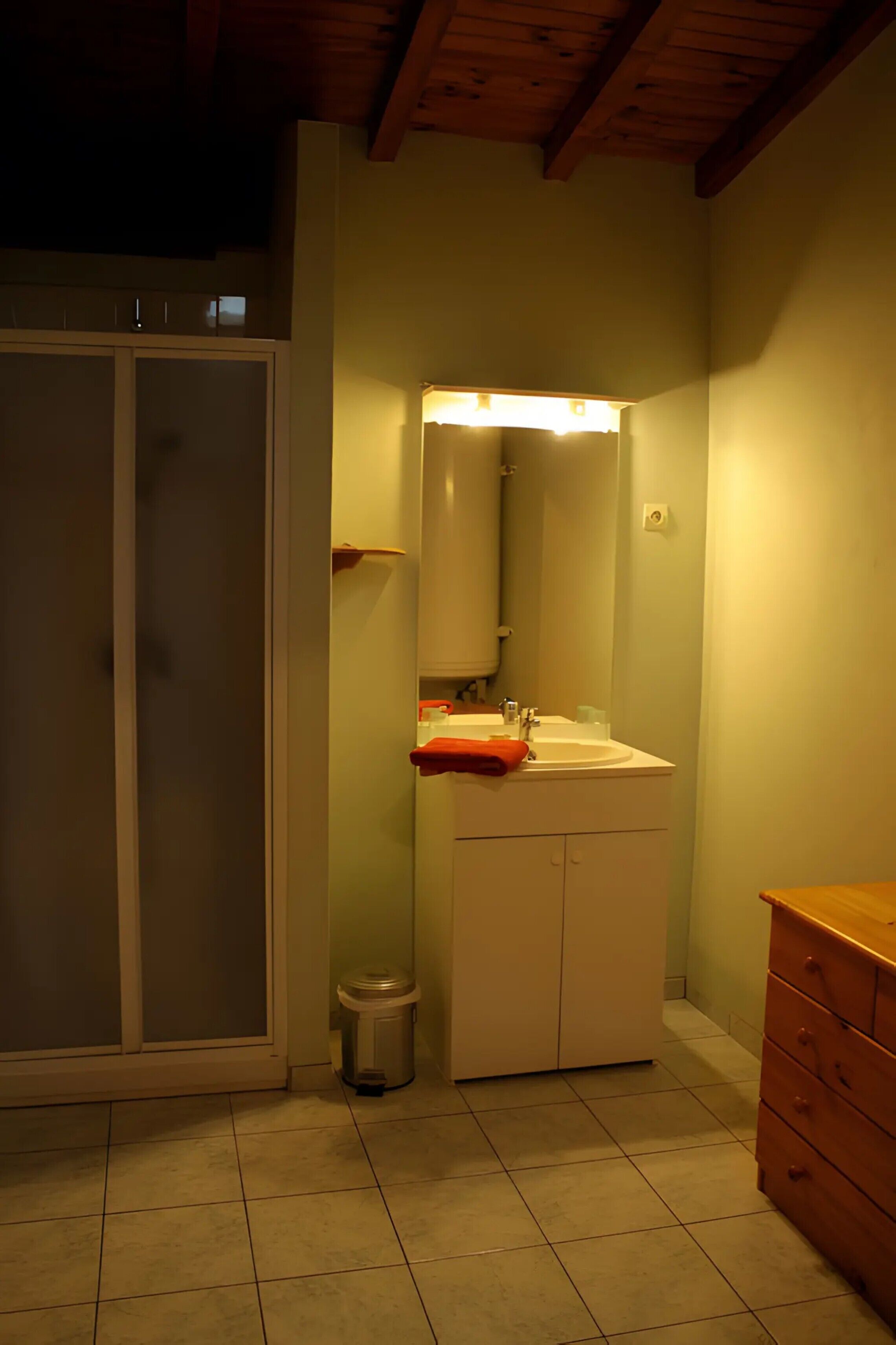 Une salle de bain avec une douche, un lavabo avec un miroir et un meuble en bois.