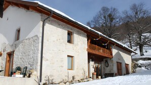 A two-story stone building with a balcony, a wooden door, and a window.