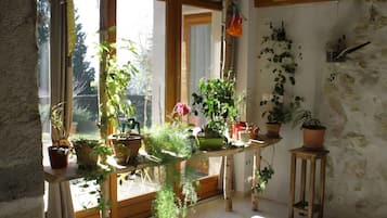 Une pièce dotée d’une grande fenêtre, d’une table en bois ornée de plantes en pot et d’un mur en pierre.