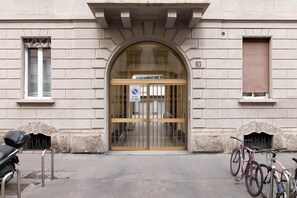 A building entrance with a large arched door, a no parking sign, and bicycles parked outside. - Charming apartment in Città Studi (Milano)