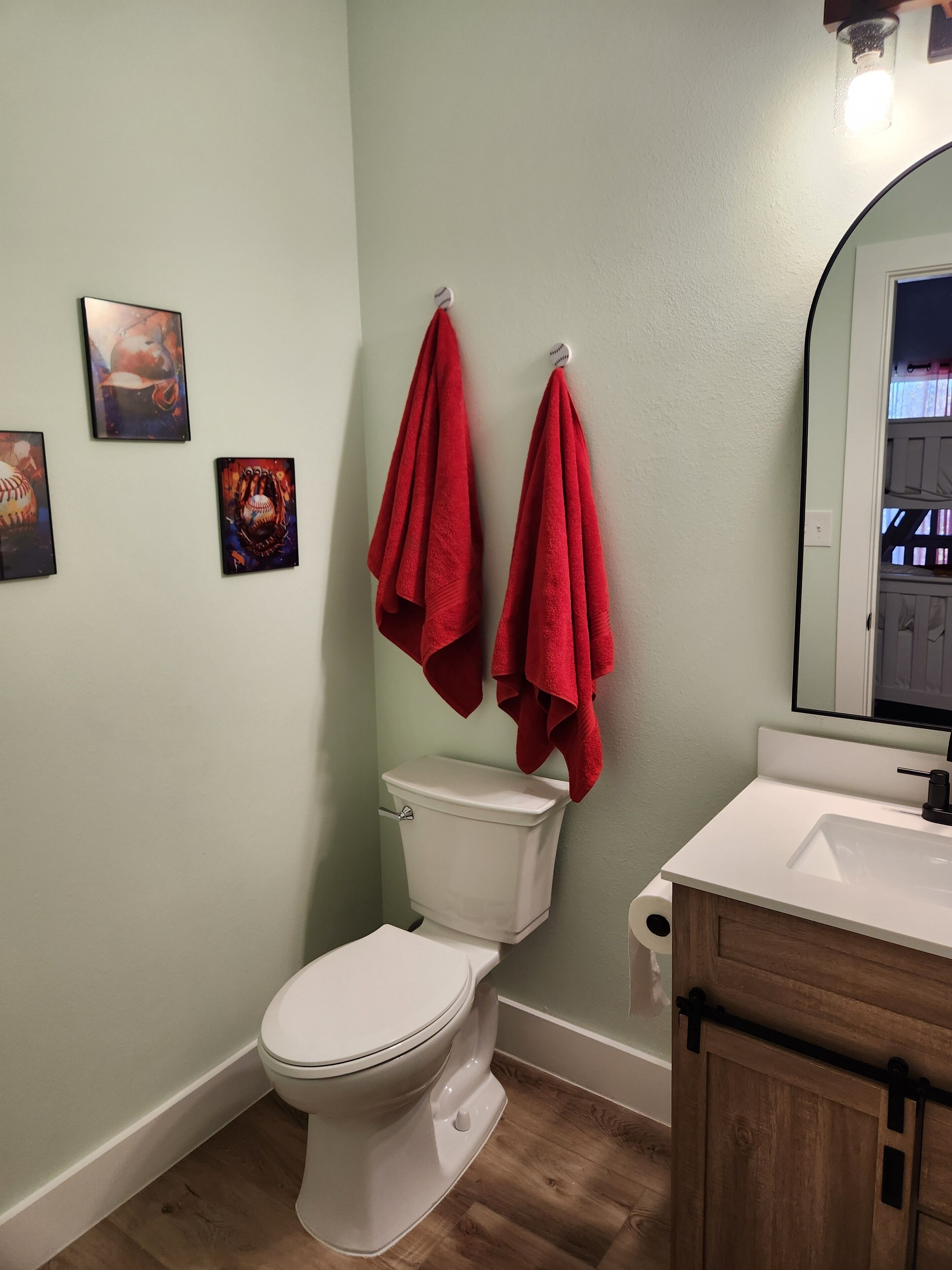 Ein Badezimmer mit Toilette, Waschbecken und zwei roten Handtüchern, die an einem Handtuchhalter hängen.