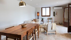 A modern living room with a wooden dining table, sofas, and a lamp. - Villa 'Ensueño' with Sea View, Wi-Fi and Air Conditioning (Calonge)